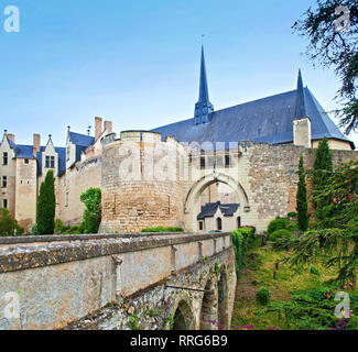 Arcuata di ponte in pietra e ingresso al maestoso Château de Montreuil-Bellay castello e le mura di cinta in Francia. Nuvoloso mattina di primavera, del prato verde Foto Stock