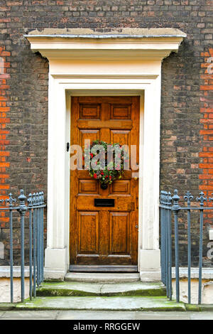 Ghirlanda di festosa appeso sulla porta di legno durante il periodo natalizio Foto Stock