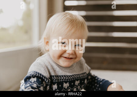 Carino adorabile piccola bionda Toddler Kid ridendo, divertendosi e rendendo Silly volti al di fuori di casa sul patio porticato schermato Foto Stock