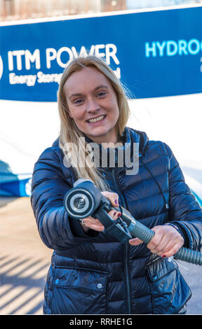 Donna sorridente che tiene un tubo di rifornimento per le automobili Di Idrogeno. Il Rifornimento rapido con idrogeno richiede solo tre minuti. Foto Stock