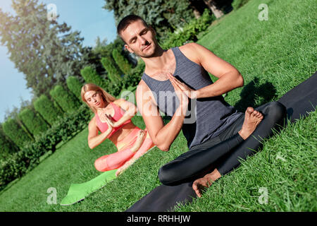 Uno stile di vita sano. Giovane a praticare yoga all'aperto seduta su Materassini da yoga occhi chiusi in meditazione Foto Stock