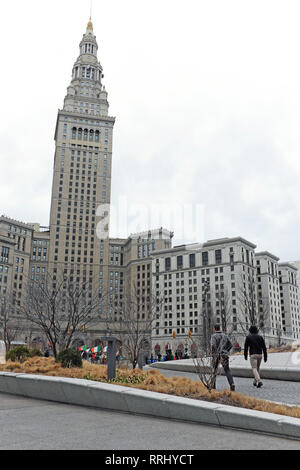 Due uomini camminano attraverso la piazza pubblica verso l'iconico Tower City Center, noto anche come Terminal Tower, in un giorno invernale coperto. Foto Stock