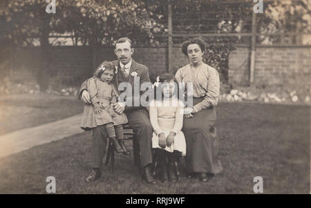 Vintage Cartolina fotografica che mostra un gruppo di famiglia. Il marito e la moglie con i loro due figlie Foto Stock