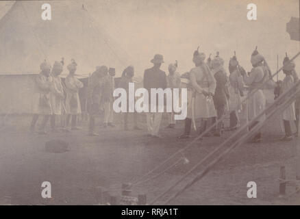 Vintage Cartolina fotografica che mostra un gruppo di soldati Sikh avente una riunione all'interno di un esercito Camp. Posizione sconosciuta. Foto Stock