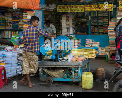 Uomo con la canna da zucchero mulino di fronte di cartoleria, Calcutta, West Bengal, India Foto Stock