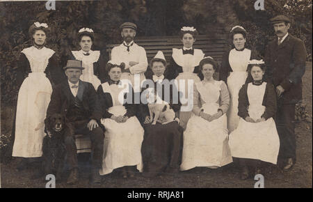 Vintage Edwardian Cartolina fotografica che mostra un gruppo di funzionari nazionali e un cane da compagnia. Foto Stock