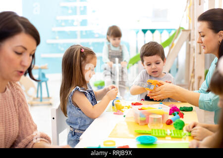 I bambini giocano di impasto nel centro diurno. I bambini lo stampo da plastilina in asilo nido. Poco gli studenti impastare la creta per modellare con le mani in età prescolare. Foto Stock