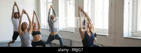 La millenaria sportivi in piedi nella posizione del guerriero durante la sessione di yoga Foto Stock