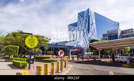 Johannesburg, Sud Africa, 5 Dicembre - 2018: ingresso del parco auto guardando verso un ufficio moderno edificio con vetro e argento riflettente esterna sunl Foto Stock