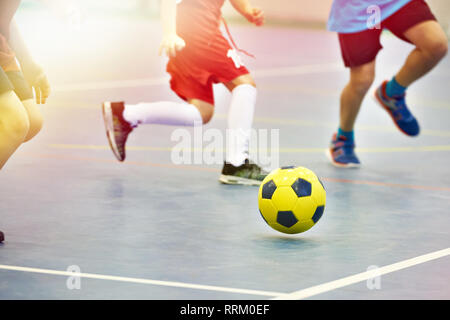 I bambini che giocano a calcio con calcio giallo in ambienti interni Foto Stock