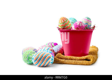 Colorate le uova di pasqua su il nido in rosso la benna con tessuto isolato su sfondo bianco. Buona Pasqua Foto Stock