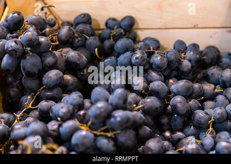 Uve fresche in vendita in una scatola di legno al mercato della frutta. Uva gustosi frutti sono ricchi di vitamine e minerali Foto Stock