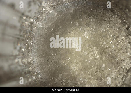 Lo zucchero al fondo di un chiaro vetro sfaccettate. Macro closeup opere d'arte. Foto Stock