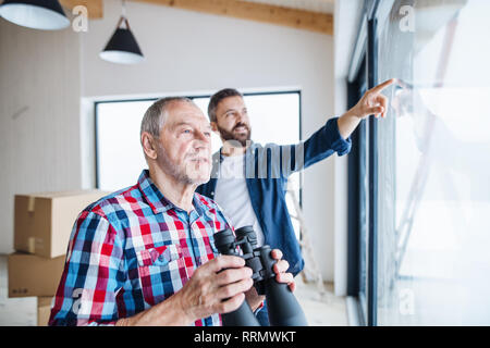 Un allegro senior uomo aiutando il suo figlio maturo con arredamento casa nuova, un nuovo concetto di casa. Foto Stock