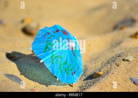 Cocktail disgarded ombrello su una spiaggia, close up photo shoot Foto Stock