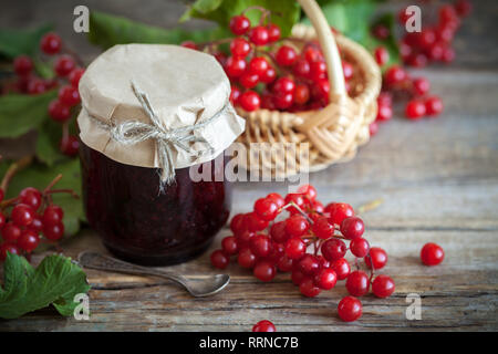 Vasetto di viburno rose (rosso) Viburnum marmellata e cestello con rosse bacche sano sullo sfondo. Foto Stock