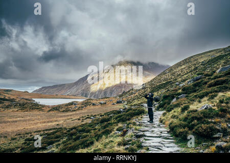 L'uomo sul percorso di pietra tra remote, paesaggio tranquillo, Snowdonia NP, REGNO UNITO Foto Stock