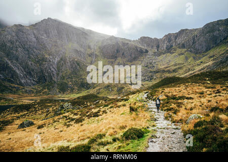 Donna che cammina lungo scoscese sentiero di montagna, Snowdonia NP, REGNO UNITO Foto Stock