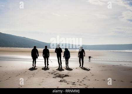 Un gruppo di persone che camminano su una tranquilla spiaggia di sabbia con la bassa marea. Woolacombe, North Devon, Inghilterra, Regno Unito, Gran Bretagna Foto Stock