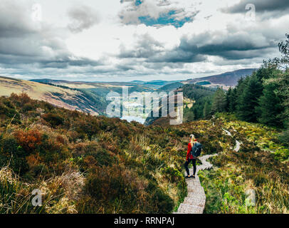 Donna escursioni lungo la montagna idilliaco percorso panoramico con vista del paesaggio, NP di Wicklow, Irlanda Foto Stock