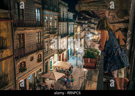 Donna in piedi sul balcone, guardando ornati in architettura, Porto, Portogallo Foto Stock