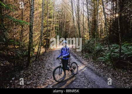 Ritratto fiducioso uomo mountain bike nei boschi di autunno, Squamish, BC, Canada Foto Stock