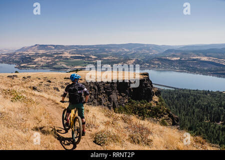 L'uomo mountain bike, godendo di Columbia River vista dalla scogliera, Hood River, Oregon, Stati Uniti d'America Foto Stock