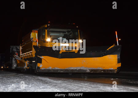 Spazzaneve a notte sulla strada sdrucciolevole in febbraio Foto Stock