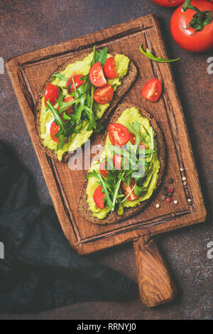 Purea di avocado di segala pane tostato servito su rustiche tagliere di legno. Tabella vista dall'alto. Vegana Vegetariana, uno spuntino o una prima colazione Foto Stock