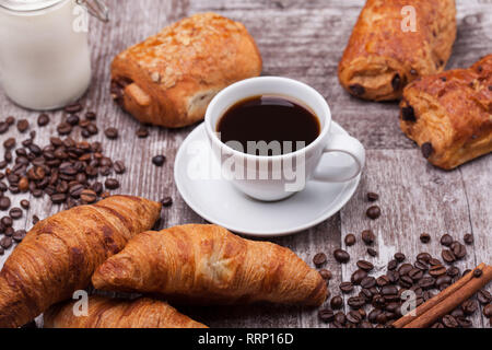 La prima colazione con prodotti freschi coissants con caffè e latte su tavola in legno rustico. Golden croissant. Foto Stock