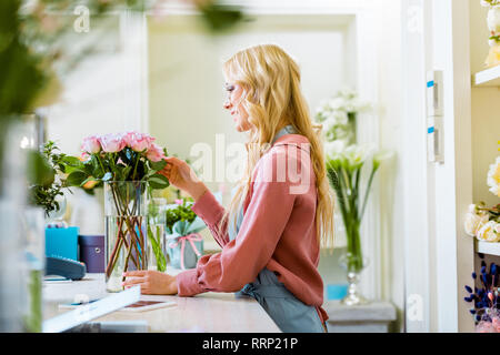 Bellissima femmina di regolazione di fiorista bouquet di rose rosa nel negozio di fiori Foto Stock