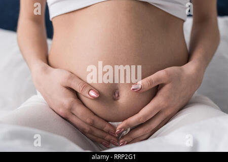 Vista ritagliata della donna incinta toccando delicatamente la pancia Foto Stock