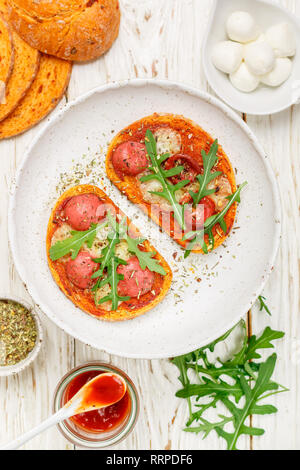 In casa aprire panini con salsiccia, mozzarella, ketchup e rucola fresca. Gourmet di pane tostato. Messa a fuoco selettiva Foto Stock