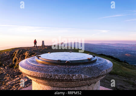 Un escursionista al toposcope alla sommità del Worcestershire Beacon, in una nebbiosa, sunrise su un inverni di mattina. Malvern Hills, UK. Foto Stock