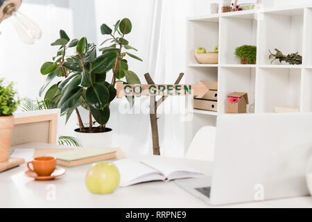 Area di lavoro con Apple e laptop vicino andare segno verde in ufficio moderno, risparmio ambientale concetto Foto Stock