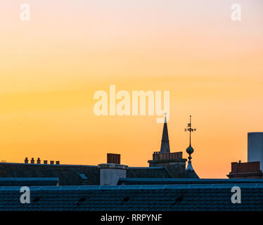 Leith, Edimburgo, Scozia, Regno Unito, 26 febbraio 2019. Regno Unito Meteo: un bagliore arancione nel cielo visto al tramonto su vecchi tetti di Leith su un record giornata invernale con i più caldi in inverno la temperatura registrata Foto Stock