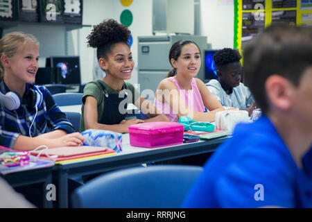 Sorridente junior high school girl gli studenti al banco in aula Foto Stock