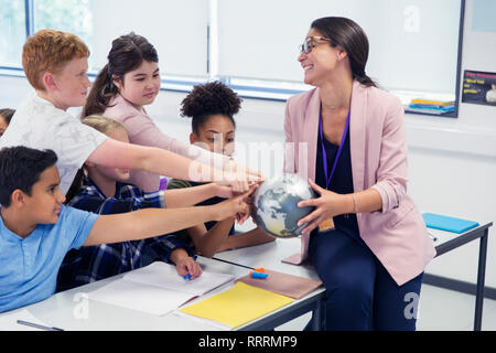 Gli studenti desiderosi di toccare globe in geografia insegnanti le mani Foto Stock