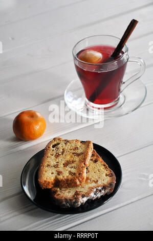 Fette di pane dolce con uvetta sulla piastra nera, servita con mandarin e apple-dewberry composta con la stecca di cannella sul bianco tavolo in legno, Foto Stock