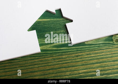 Bianco tagliato in legno di casa su sfondo verde Foto Stock