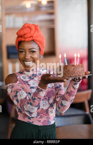 Ritratto fiducioso giovane donna che porta la torta di compleanno Foto Stock