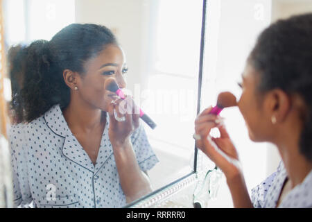 Giovane donna ottenere pronto, applicando il trucco in Specchio bagno Foto Stock