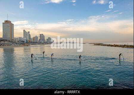 Un gruppo di stand up paddle boarders praticando la mattina presto spento la spiaggia urbana di Tel Aviv, Israele Foto Stock