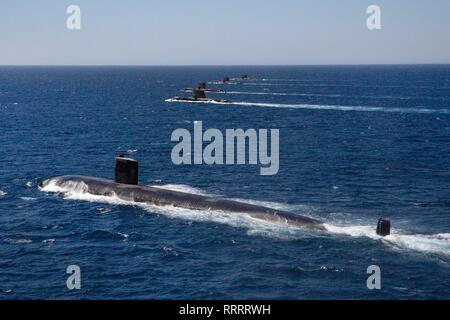 Gli Stati Uniti Navy Los Angeles-class attack submarine USS Santa Fe vele in formazione con Royal Australian Navy Collins sommergibili classe HMAS Collins, HMAS Farncomb, HMAS Dechaineux e HMAS Sheean, come un australiano MH-60R Seahawk elicottero vola overhead in West Australian zona di esercizio di Febbraio 18, 2019 al largo di Fremantle, Australia. Foto Stock