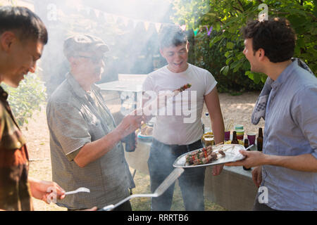 Amici maschi godendo barbecue nel cortile posteriore Foto Stock