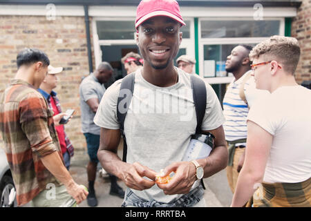 Ritratto fiducioso uomo mangiare orange in parcheggio Foto Stock