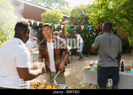 Amici maschi godendo di backyard barbecue estivi Foto Stock