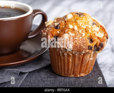 Primo piano di un chocolate chip muffin e tazza di caffè su un tovagliolo grigio Foto Stock