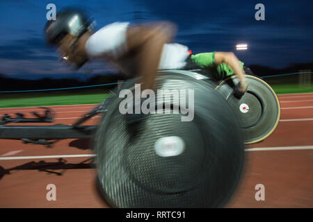 Gli atleti paraplegici accelerando lungo la via dello sport in carrozzella gara in notturna Foto Stock