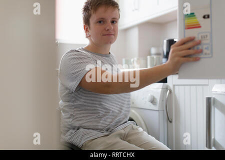 Confidente Ritratto di giovane donna in sedia a rotelle in appartamento cucina Foto Stock